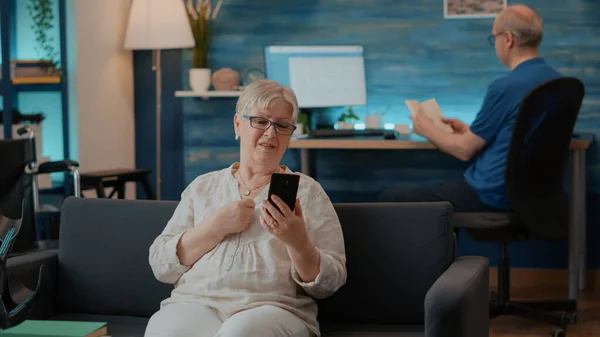 上了年纪的女人在客厅里用遥控电话聊天 — 图库照片