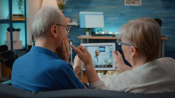 Homem e mulher idosos conversando com dentista em videochamada online — Fotografia de Stock