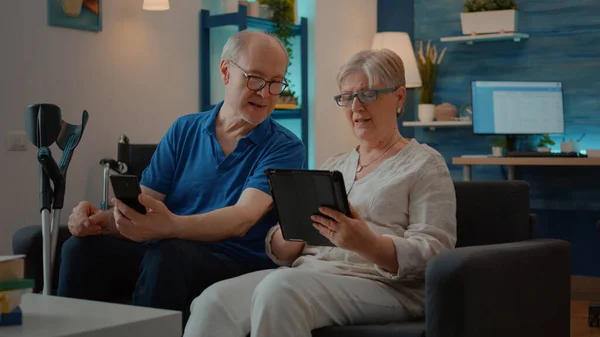 Grootouders die thuis smartphone en digitale tablet gebruiken — Stockfoto
