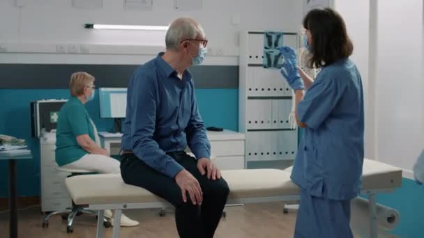 Verpleegster en oude man kijken naar radiografie scan diagnose — Stockvideo