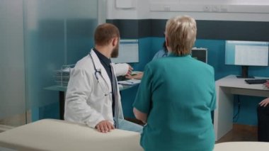 Emeklilik yaşındaki hasta ofiste check-up dosyalarını imzalıyor