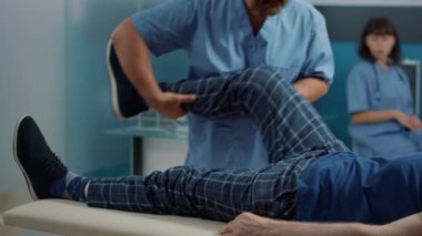 Erkek osteopat kemik kırıyor ve bacak kasları geriliyor.