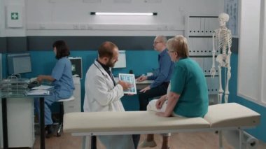 Tabletteki röntgen tarama sonuçlarını inceleyen doktor ve yaşlı kadın