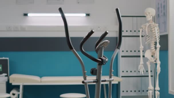 Fizik tedavisinde kullanılan durağan bisikleti olan boş bir tıbbi ofis. — Stok video