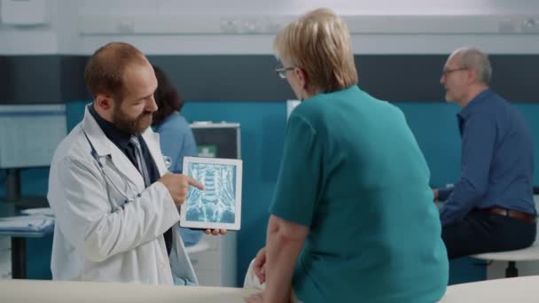 Ιατρός και ηλικιωμένος ασθενής που εξετάζουν τα αποτελέσματα ακτινογραφίας — Αρχείο Βίντεο