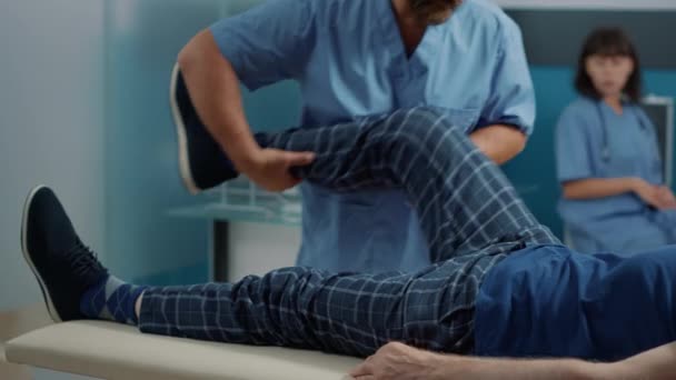 Manlig osteopat sprickbildning ben och stretching ben muskler — Stockvideo