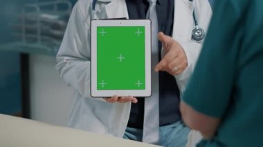 Fizyoterapist dijital tablette dikey olarak yeşil ekran tutuyor