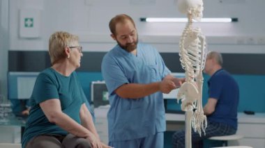 Erkek osteopat insan iskelet kemiklerindeki sırt ağrısını açıklıyor