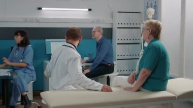 Erkek doktor ve yaşlı hasta radyografi sonuçlarına bakıyor.