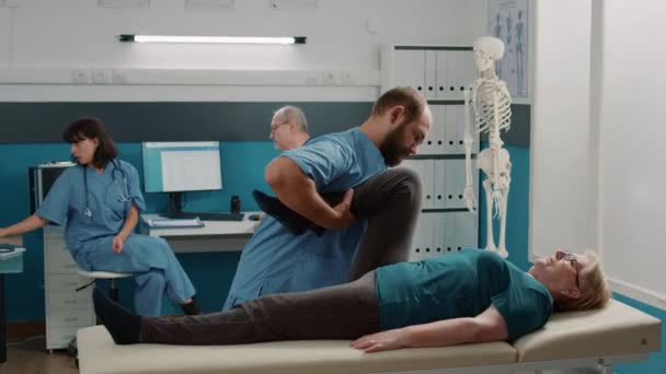 Médecin et vieux patient faisant des jambes soulever l'exercice pour aider à la récupération — Video