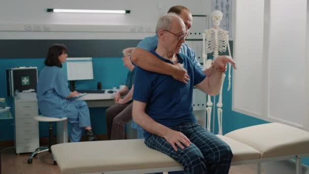Практикуючий чоловік використовує процедуру підняття рук, щоб допомогти пацієнту похилого віку — стокове відео