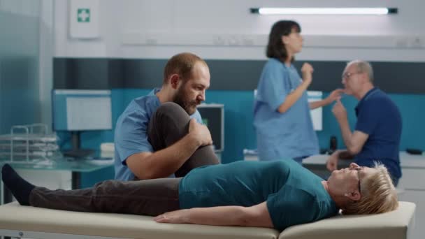 Терапевт використовує вправи для підняття ноги на літню людину, щоб зламати кістки — стокове відео