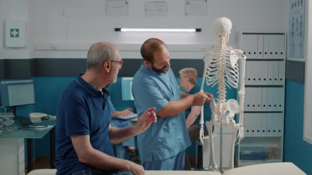骨脊髄を老人に見せるセラピスト — ストック動画