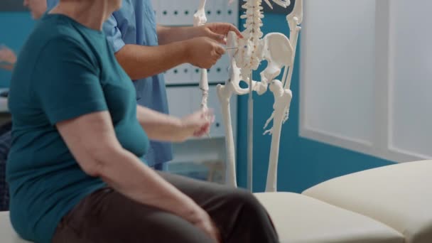 脊髄を示すために人間の骨格を指している男性医師 — ストック動画