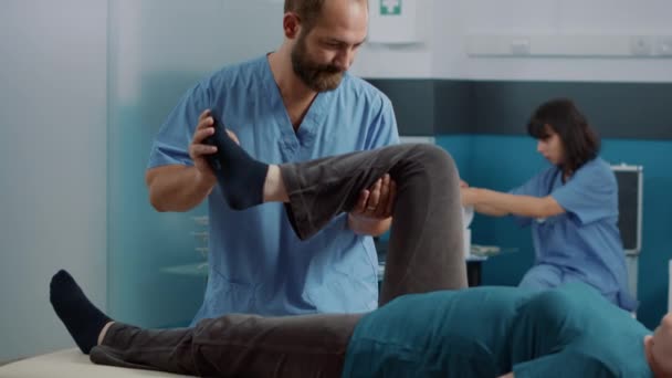 Erkek terapist bacak kaslarını germek için ortopedik egzersiz yapıyor. — Stok video