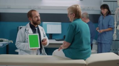 Erkek doktor dijital tableti dikey olarak yeşil ekran ile tutuyor