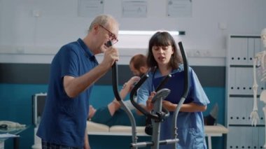 Fizik tedavi gören kıdemli bir adamı destekleyen tıbbi asistan.