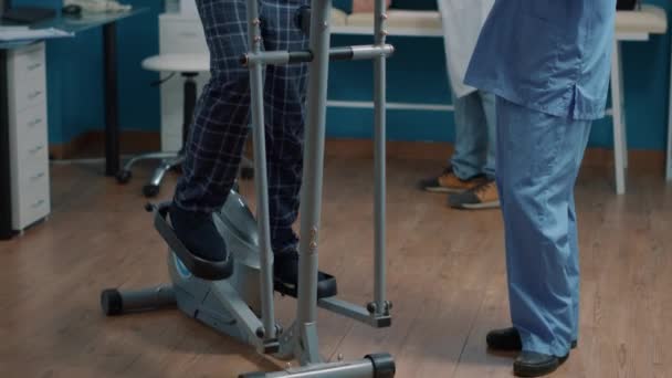 Медсестра надає медичну допомогу пацієнту на стаціонарному електричному велосипеді — стокове відео