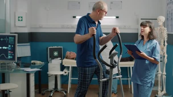 Enfermera médica que ayuda al paciente anciano a hacer ejercicio físico — Vídeos de Stock