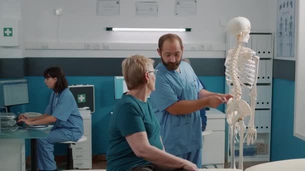 Physiotherapeut zeigt auf Rückenmark am menschlichen Skelett — Stockvideo