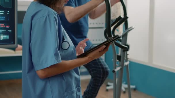 Жіноча медсестра використовує цифровий планшет та допомагає літнім пацієнтам — стокове відео