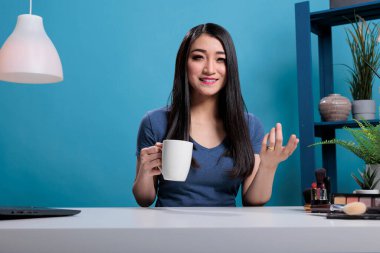 Güzellik içeriğini kaydederken kameraya gülümseyen Asyalı kadın vlogger