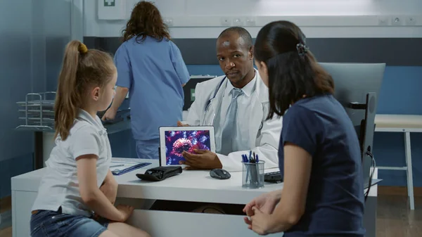 タブレットディスプレイ上でコロナウイルスイラストを説明する医師 — ストック写真