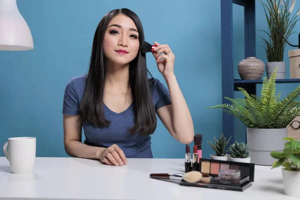 Asyalı vlogger kamerada fırça kullanarak makyaj dersi veriyor