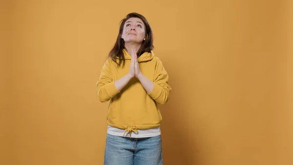 Tillfällig kvinna känner sig orolig, tittar upp be och ber om förlåtelse med handflatorna nära varandra — Stockfoto