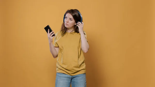 Mujer usando smartphone escuchando música en auriculares inalámbricos y bailando — Foto de Stock