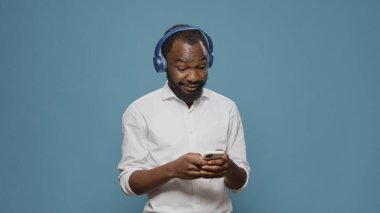 Neşeli insan kulaklıkla müzik dinliyor ve akıllı telefon kullanıyor.