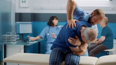 Fizyoterapist, yaşlı adamın kemiklerini kırmasına yardım ediyor.