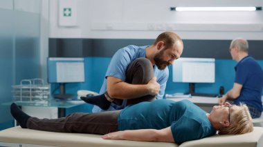 Terapist, kemikleri kırmak için yaşlı insanlar üzerinde bacak kaldırma egzersizi yapıyor.