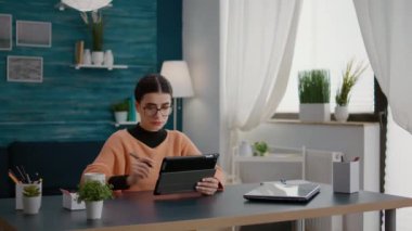 Sınıf ödevi üzerinde çalışmak için dijital tablet kullanan öğrenci