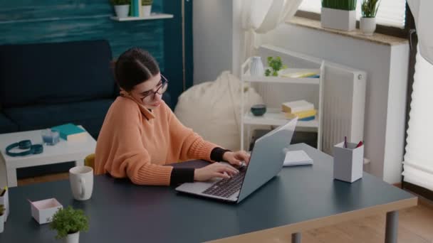 Estudante conversando por telefone e trabalhando no laptop em casa — Vídeo de Stock
