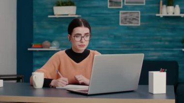 Ders kitabı üzerine not alan ve video konuşmasında konuşan genç kişi