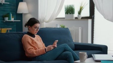 Üniversite öğrencisi evdeki akıllı telefondan internette geziniyor.