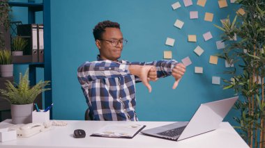 Satış uzmanı dizüstü bilgisayarın önünde baş parmak hareketi yapıyor.