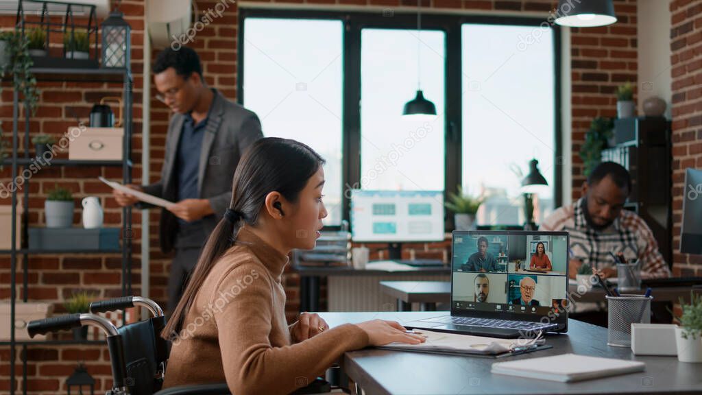 Woman attending videocall meeting on laptop with disability friendly office