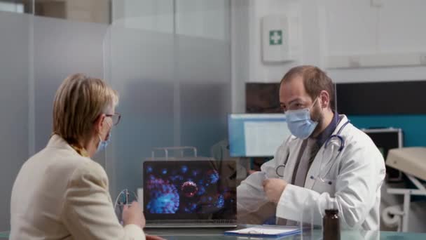 Specjalista od zdrowia pokazując ilustrację wirusa na laptopie do starszej kobiety — Wideo stockowe