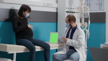 Hamile kadın ve doktor dijital tablette yeşil ekrana bakıyor