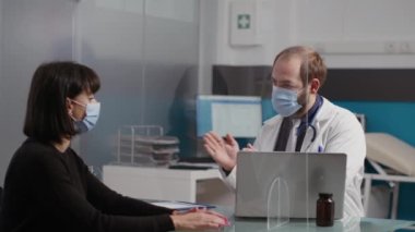 Check-up ziyareti sırasında bir kadınla konuşan doktor.