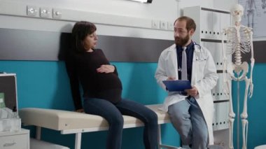 Sağlık uzmanı, sağlık dolabındaki hamile kadına danışıyor.