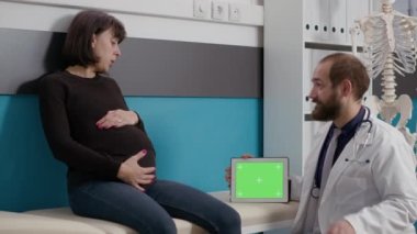 Yatay yeşil ekran kullanan hamile karnı ve doktoru olan hasta.