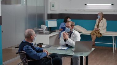 Doktor tekerlekli sandalyedeki hastaya muayene yapıyor.