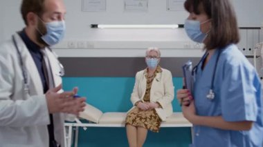 Doktor ve kadın hemşire hastaları muayene etmek için kontrol dosyalarını inceliyor.