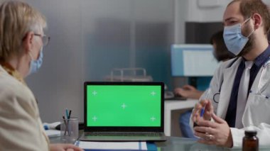 Kontrol ziyareti sırasında laptopta yeşil ekrana bakan yaşlı kişi