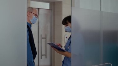 Erkek doktor yaşlı bir hastayla radyografi taraması yapıyor.