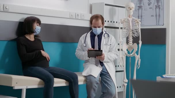 男性医師が診察時にデジタルタブレットでメモを取る — ストック動画