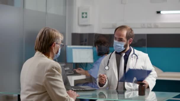 Männlicher Arzt macht sich Notizen auf Checkup-Dateien, um Rezept zu geben — Stockvideo